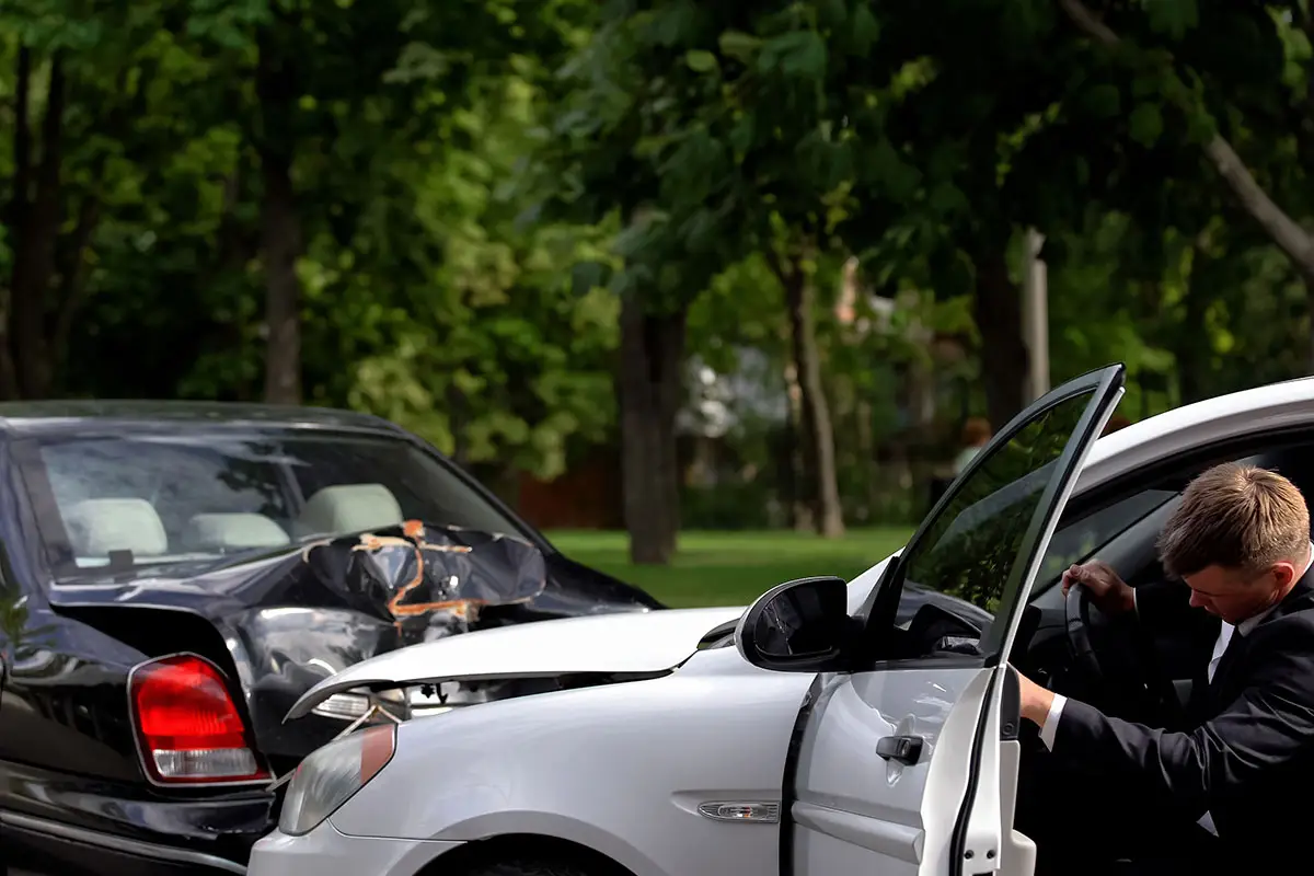A white car rear-ends a black car causing damage to both vehicles.