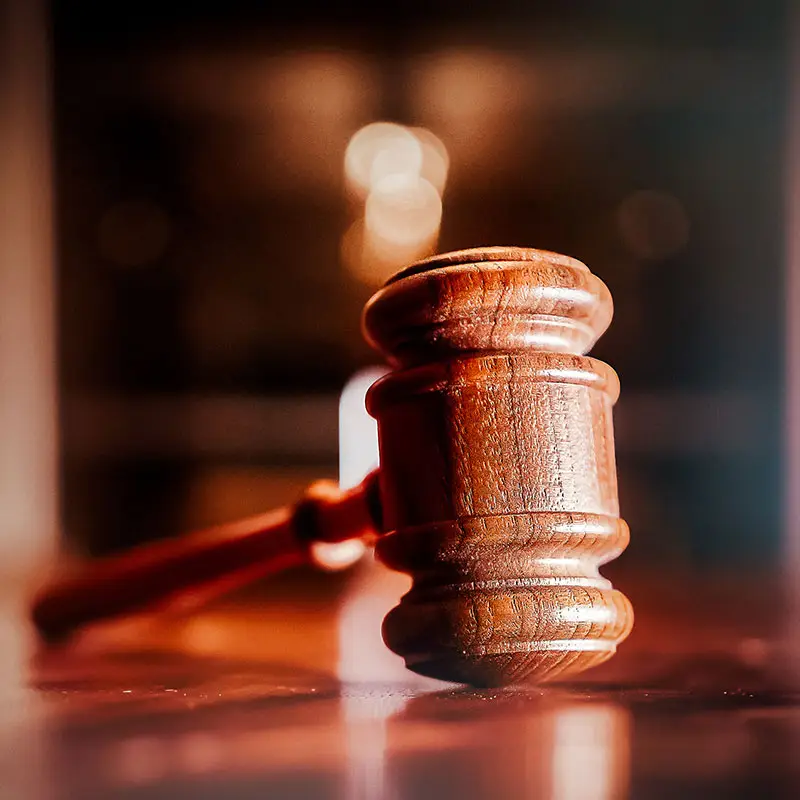 A wooden gavel is on top of a wooden table.