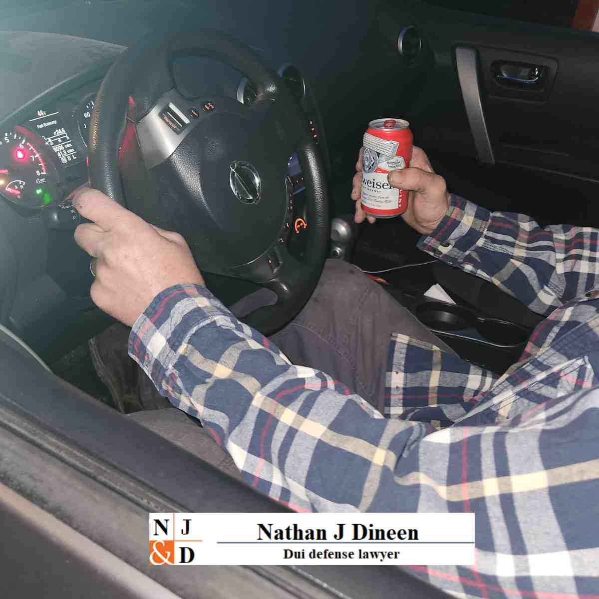 A man is holding a beer can with his left hand wile driving.