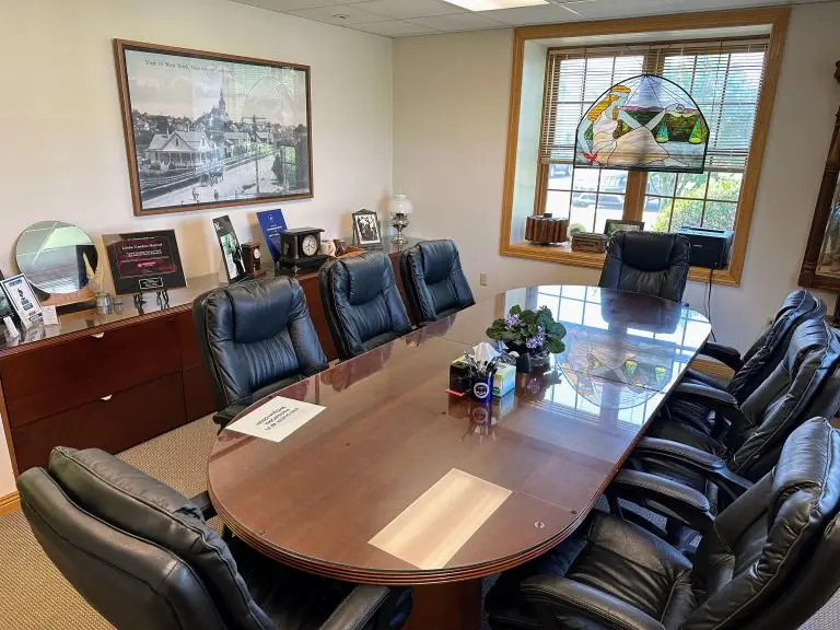 A small conference room with black leather chairs and wooden table.
