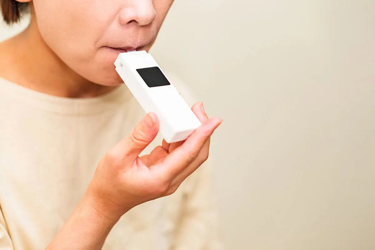 A woman is taking a breathalyzer test.