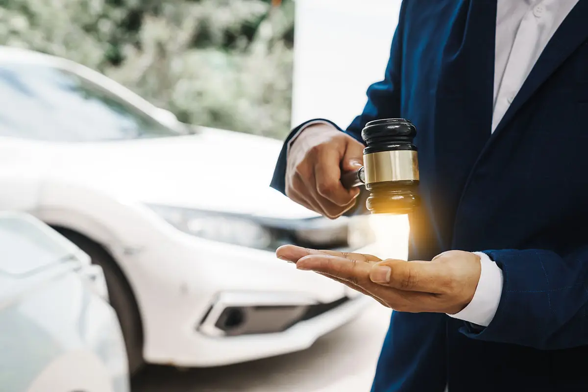 A judge wearing a suit is holding a gavel with his right hand and about to pound it on the palm of his left hand.